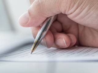 Close up of hand holding pen filling out form